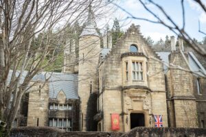 鮮やかな青空と太陽の下、階段の先に見える重厚な石造りのロックハート城。春の陽光を浴びた美しい古城の全景。