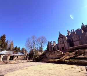 鮮やかな青空の下、広角で撮影されたロックハート城。左側の石造りの建物、お城へ続く階段、右側の古城が並び、中世ヨーロッパの街角のような奥行きのある風景。