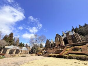 鮮やかな青空の下にそびえる、中世スコットランドの古城。石造りの外観と高い塔が印象的な、ロックハート城の美しい全景。