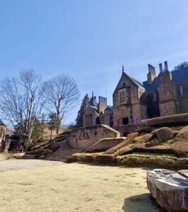 鮮やかな青空の下、お城へと続く石造りの階段と、その先にそびえ立つ重厚なロックハート城。春の陽光が降り注ぐ、卒業旅行やお出かけにぴったりの開放感あふれる絶景。