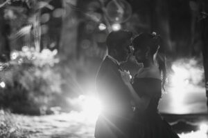 モノクロームの光の中で、額を寄せ合い静かに抱き合う新郎新婦。**「ポインセチア」**の苞（ほう）が蕾を優しく包み込むように、互いを慈しみ守り合う抱擁を表現している。群馬県「ロックハート城」の聖なる夜、二人の運命を祝福するようなドラマチックなウェディングフォト。