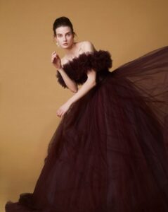 ロックハート城。中世ヨーロッパの古城を背景に、ボリュームのあるダークブラウンのチュールドレスと大ぶりのビジューイヤリングを着用した、気品漂う花嫁。