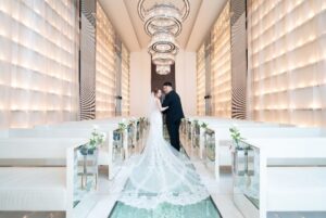 ロックハート城。歴史ある石造りのチャペルで、ウェディングドレスとタキシード姿の新郎新婦が向き合う、クラシックで重厚感あふれる結婚式風景。
