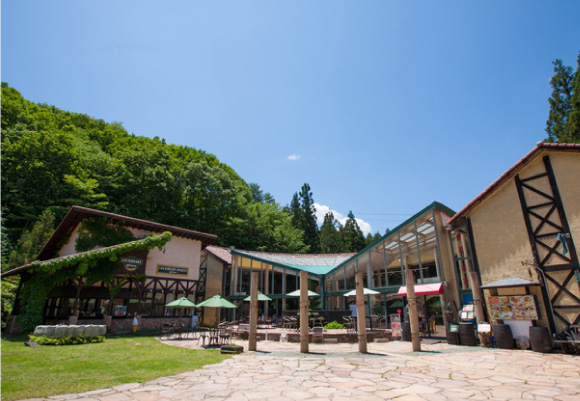 石造りの建物とユニオンジャックの旗が飾られた英国風の広場にあるレストランの入り口。手前には料理写真が載った「Grand Menu」と「Dessert Menu」の大きな看板が立っている。