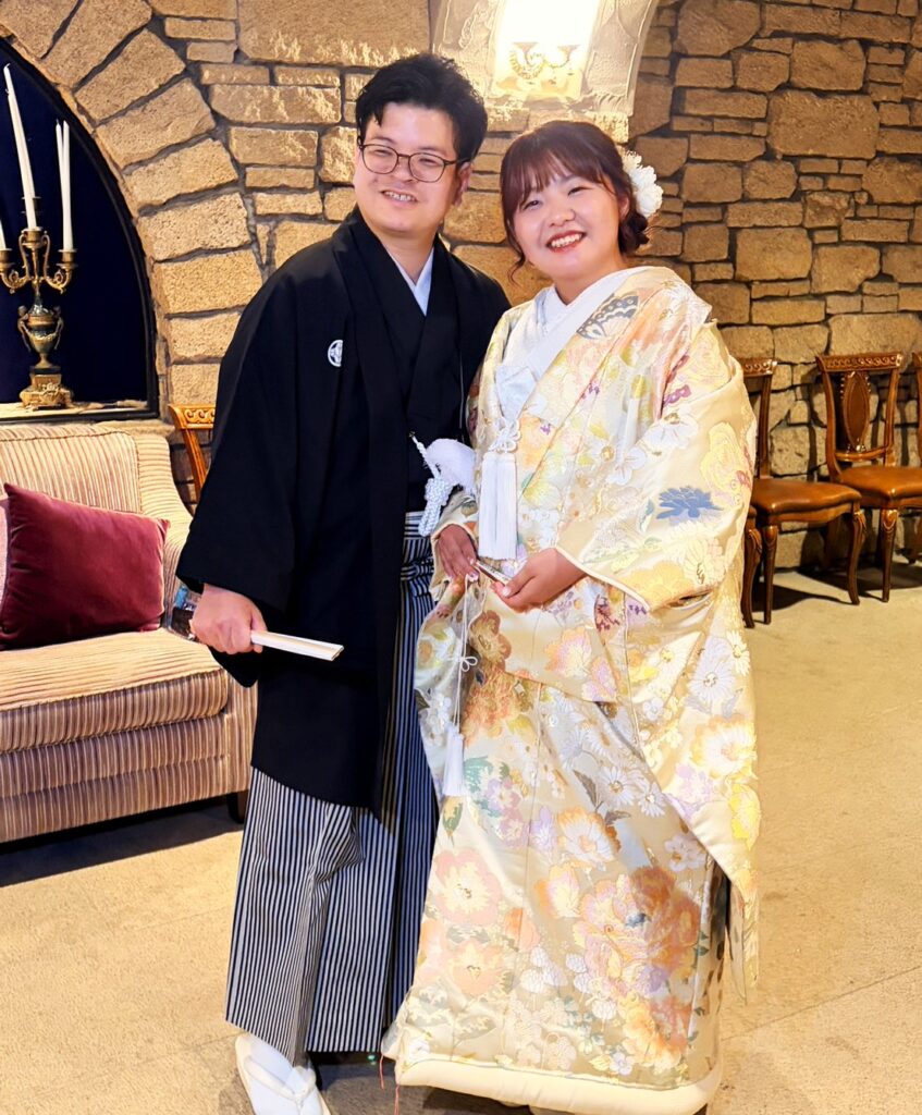 群馬県高山村のロックハート城にて、石造りのクラシックな室内で笑顔を見せる紋付袴の男性と色打掛の女性。