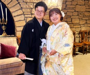 群馬県高山村のロックハート城にて、石造りのクラシックな室内で笑顔を見せる紋付袴の男性と色打掛の女性。