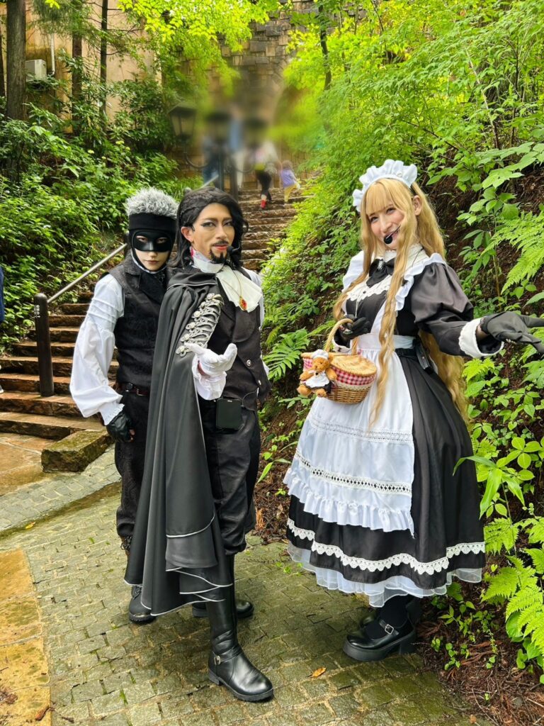 ロックハート城の園内で、ダグラスバトラーズのキャスト3名が緑豊かな小径に立ち、来園者を迎えている様子。中世ヨーロッパ風の衣装を身にまとい、記念撮影スポットとして人気の雰囲気が伝わる一枚。