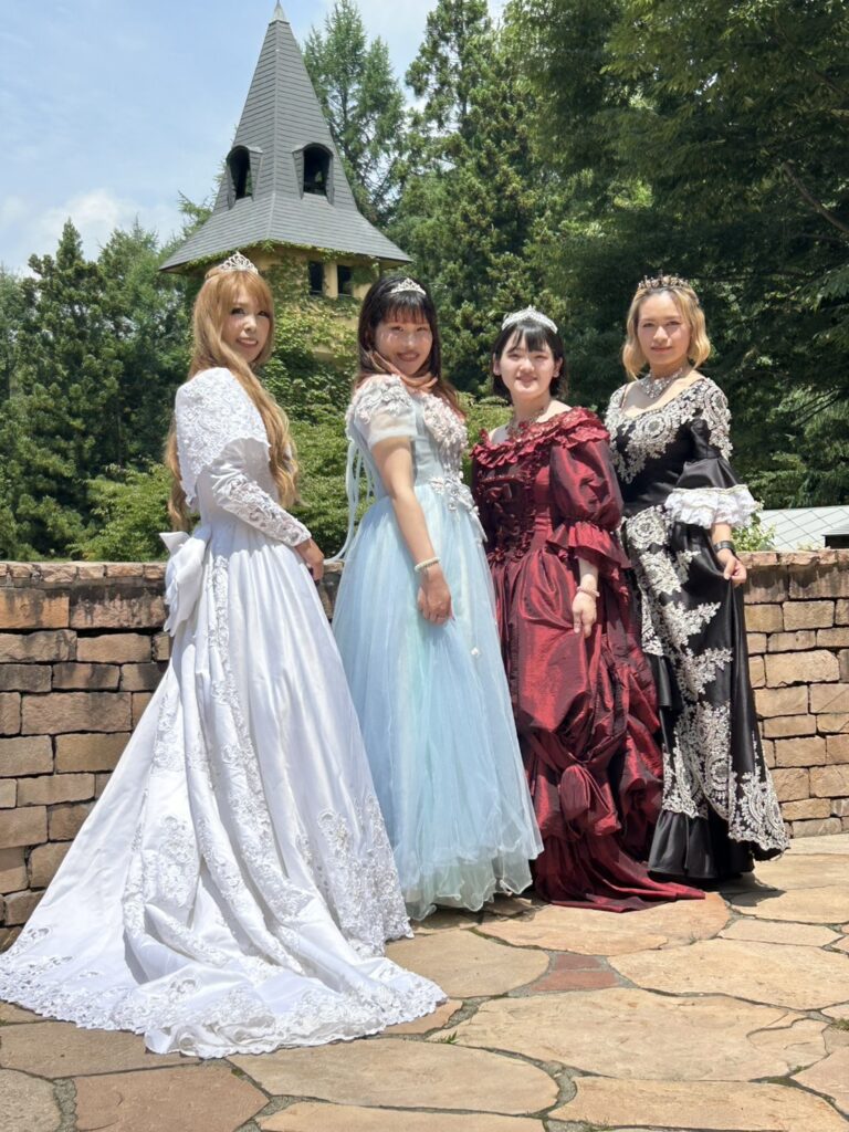 ロックハート城でプリンセス体験を楽しむ4名の女性。色とりどりのドレスを着て、お城のガーデンで記念撮影をしている様子。